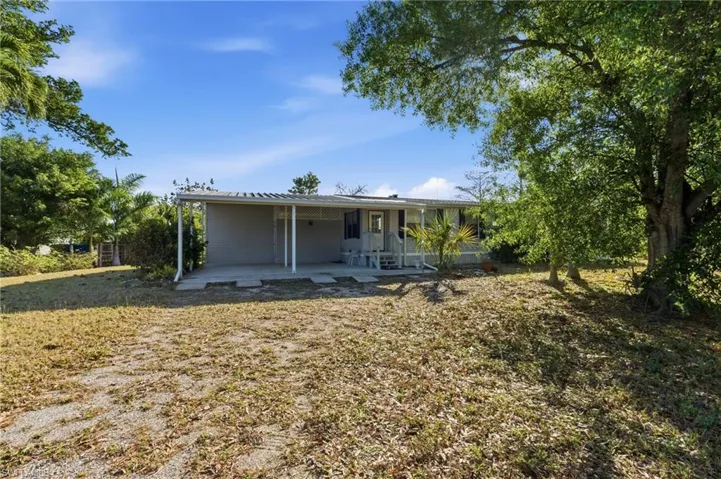 View of front of house with a patio, an attached carport, and a front yard