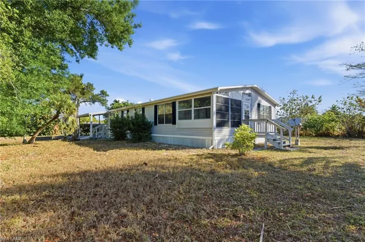 View of property exterior featuring a sunroom and a lawn