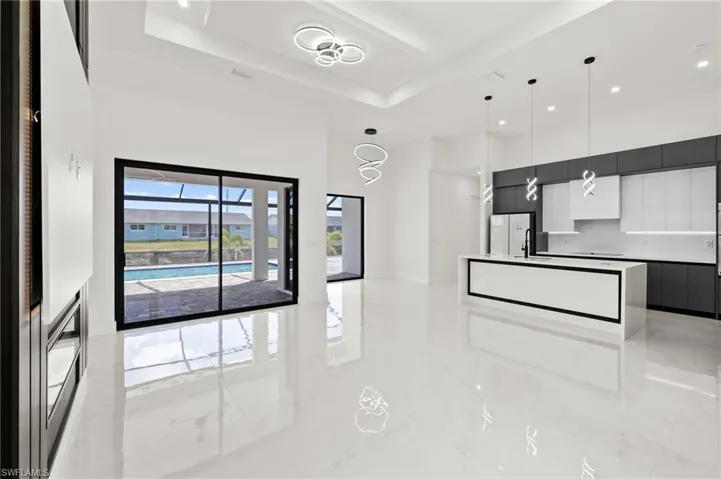 Kitchen featuring pendant lighting, modern cabinets, a center island, a high ceiling, and a raised ceiling