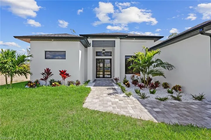 Property entrance featuring french doors, stucco siding, and a lawn