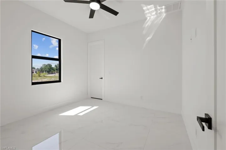 Unfurnished room featuring marble finish floor, baseboards, and a ceiling fan
