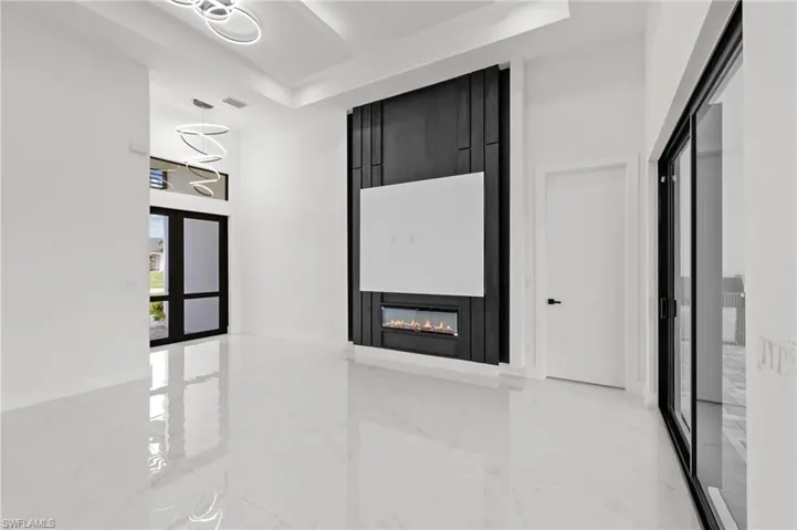 Hall featuring baseboards, a raised ceiling, marble finish floor, and an inviting chandelier
