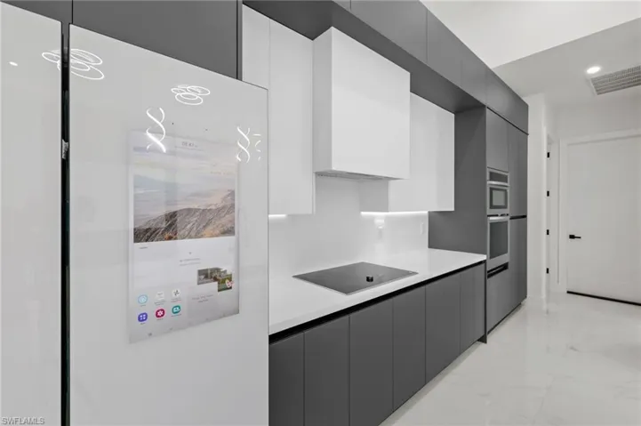 Kitchen with visible vents, black electric cooktop, modern cabinets, light countertops, and marble finish floor