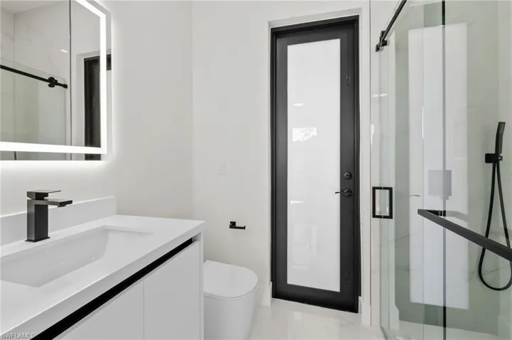 Full bath featuring toilet, a stall shower, vanity, and marble finish floor