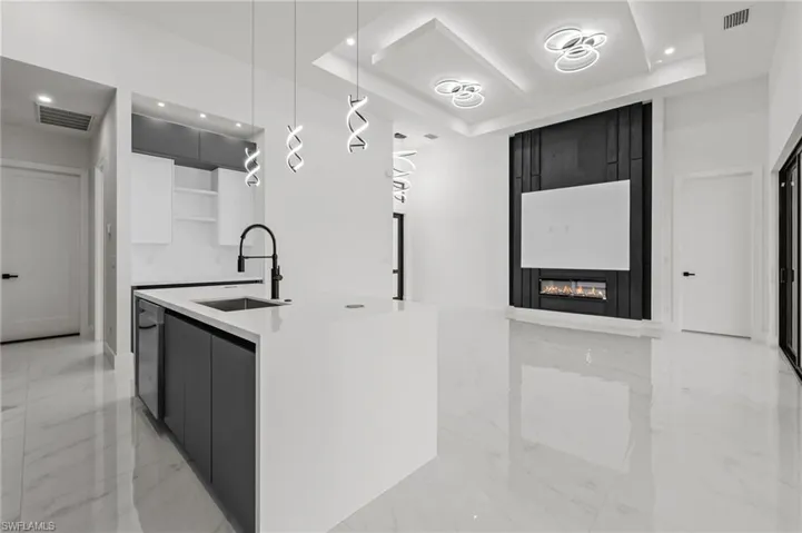 Kitchen featuring a tray ceiling, open shelves, a sink, and modern cabinets