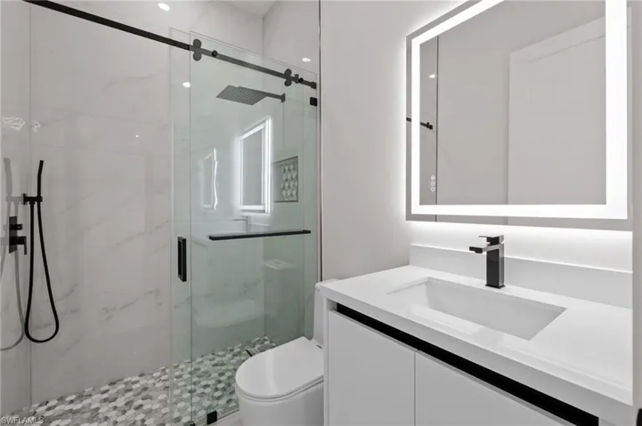 Full bath featuring vanity, a marble finish shower, and toilet