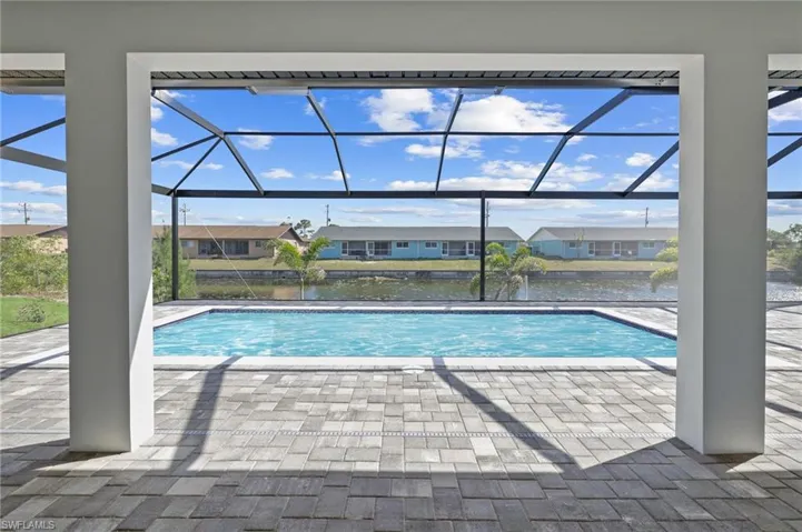 Outdoor pool with a water view, a patio, a residential view, and glass enclosure