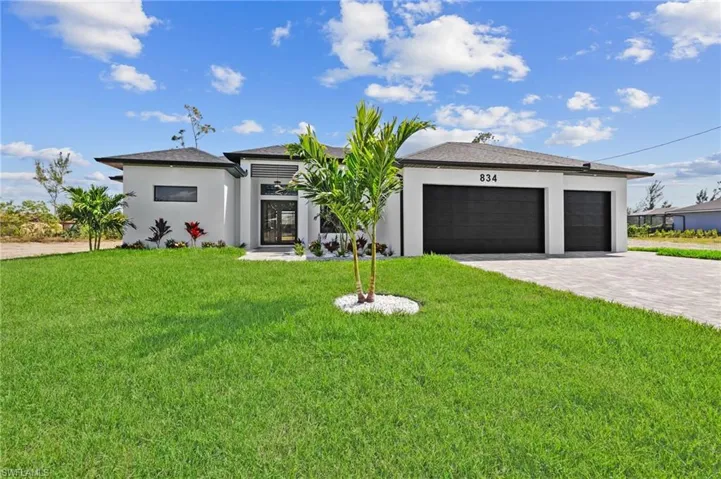 View of front facade with a garage, stucco siding, decorative driveway, and a front lawn