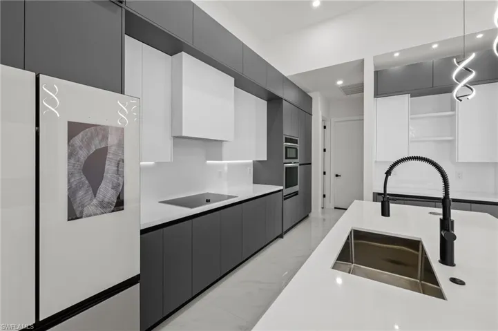 Kitchen featuring open shelves, marble finish floor, a sink, decorative light fixtures, and black electric stovetop