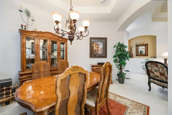 Dining area with crown molding, a notable chandelier, and a raised ceiling