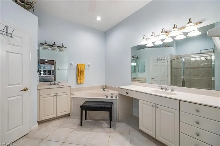 Bathroom featuring vanity, shower with separate bathtub, and tile patterned flooring