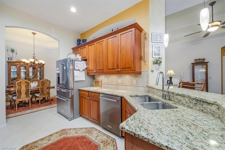 Kitchen with tasteful backsplash, sink, light tile patterned flooring, stainless steel appliances, and light stone counters