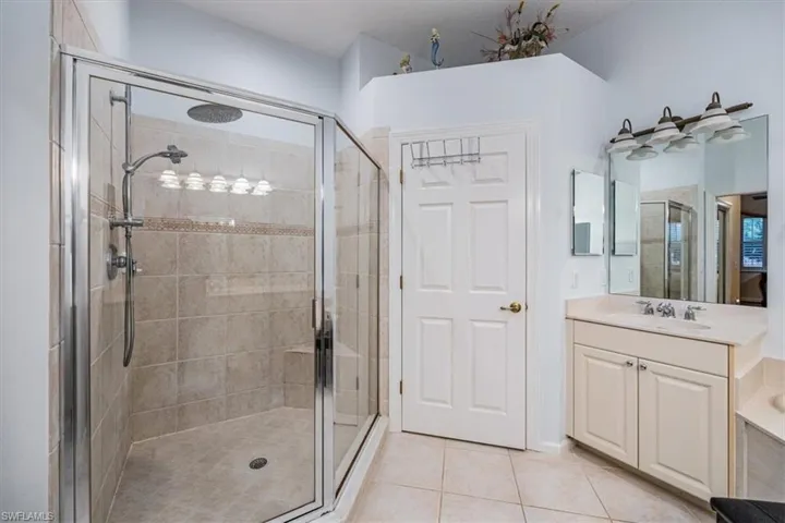 Bathroom with vanity, a shower with shower door, and tile patterned flooring