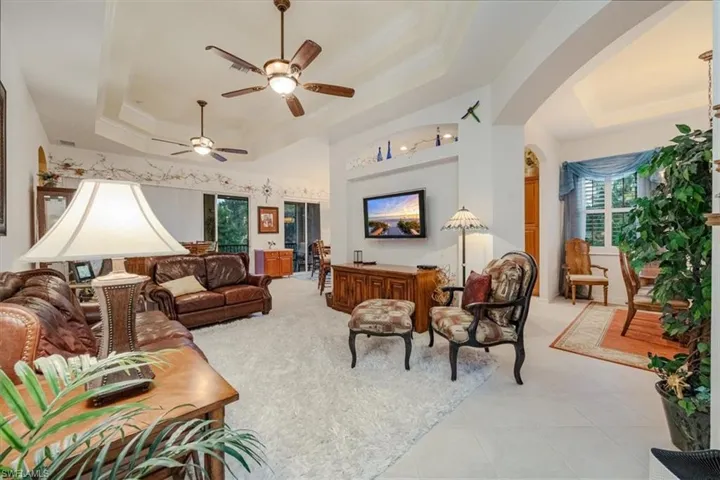 Living room with ceiling fan, ornamental molding, a tray ceiling, and light tile patterned floors
