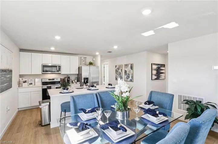 Model home. Dining room with light wood-style flooring and recessed lighting