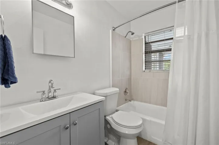 Full bath featuring shower / tub combo with curtain, toilet, and vanity