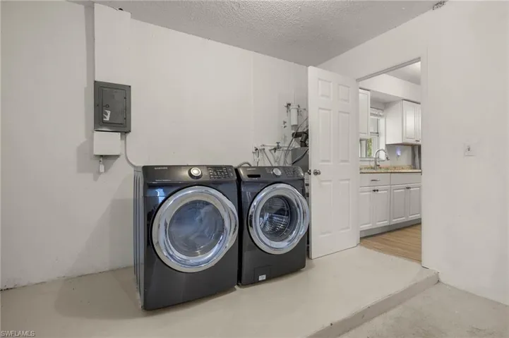 Laundry area featuring washer and clothes dryer, electric panel, and a textured ceiling