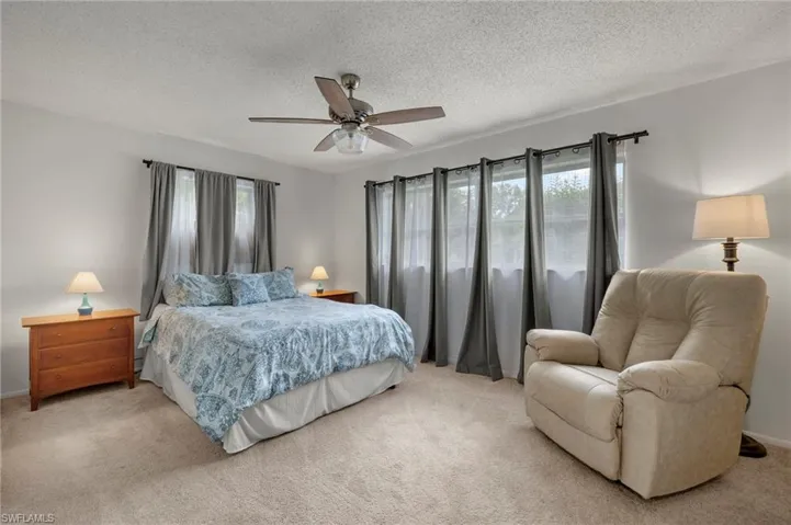 Bedroom featuring multiple windows, carpet floors, a textured ceiling, and a ceiling fan