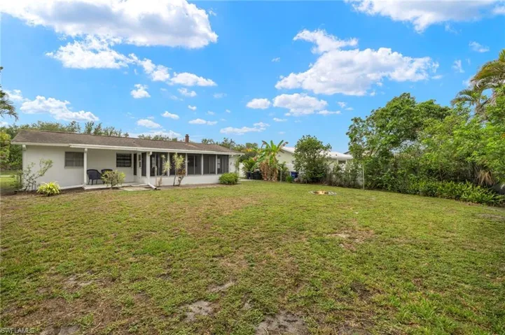 View of grassy yard featuring a sunroom
