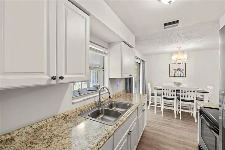 Kitchen featuring electric range, a sink, white cabinets, a chandelier, and light countertops