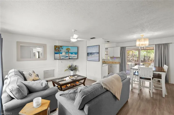 Living area with a chandelier, a textured ceiling, wood finished floors, baseboards, and a ceiling fan