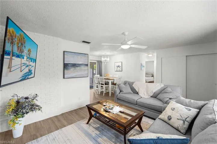 Living area with wood finished floors, a chandelier, a textured ceiling, and a ceiling fan