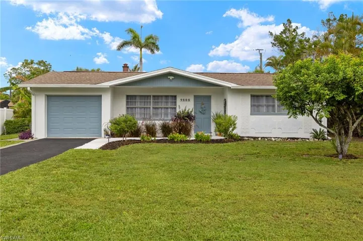 Ranch-style house featuring an attached garage, asphalt driveway, and a front yard