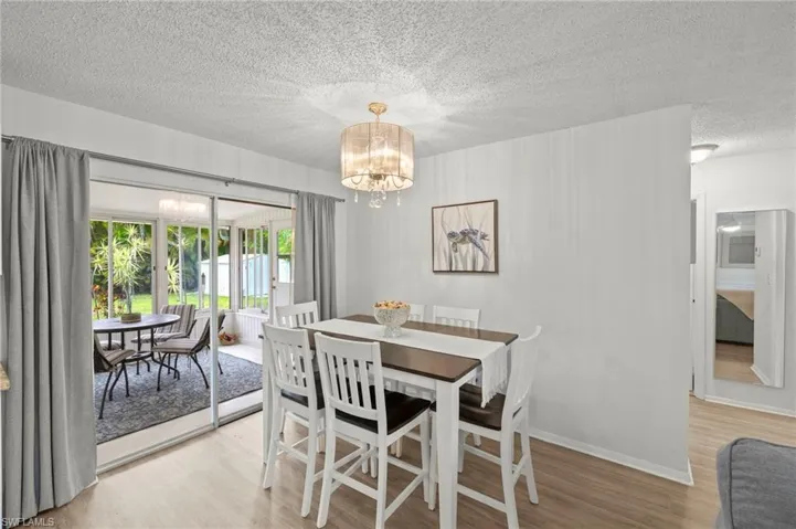 Dining area featuring a chandelier, light wood-style floors, a textured ceiling, and baseboards