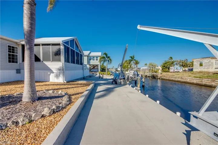 Dock area featuring boat lift, a water view, and a sunroom