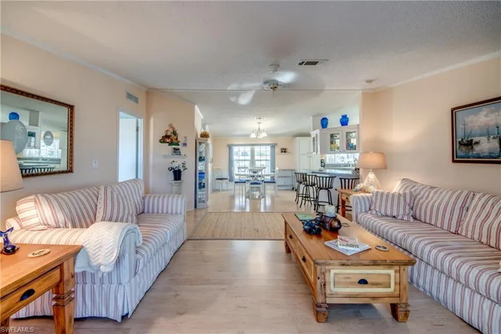 Living area with ornamental molding, light wood finished floors, a textured ceiling, and ceiling fan