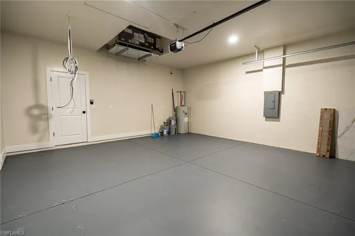 Spacious garage featuring a durable gray floor coating, a white access door, an automatic garage door opener, and recessed ceiling lighting