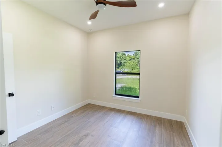 Neutral-toned room with wood-finish flooring, recessed lighting, and a modern ceiling fan