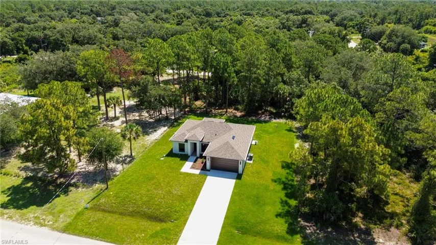 Contemporary single-story residence featuring a neutral exterior, a private driveway, an attached garage, and a lush green lawn