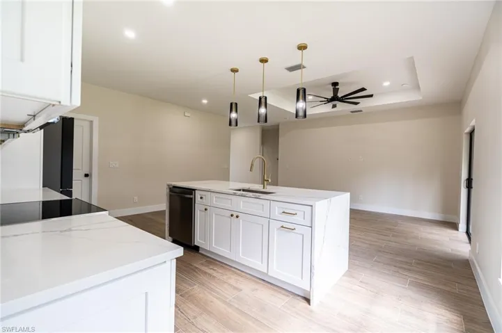 Kitchen island featuring a waterfall countertop, undermount sink, and gold-finish faucet