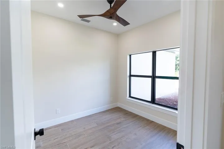 Room featuring wood-finish flooring, a modern ceiling fan, recessed lighting, and a large window with black framing