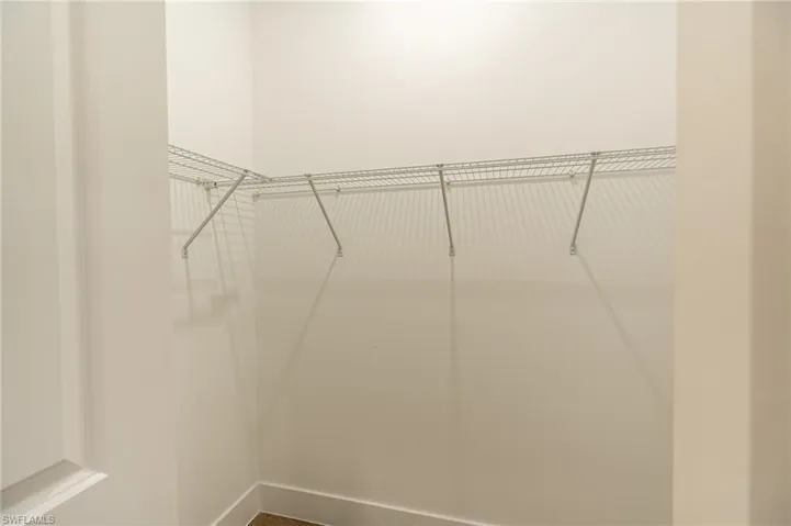 Corner closet with wire shelving system and light-toned walls