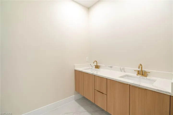 Floating double vanity with wood-finish cabinetry, white stone-look countertop, and gold-tone fixtures