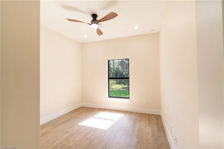 Interior room featuring wood-finish flooring, a contemporary ceiling fan, recessed lighting, and a single window with a dark frame