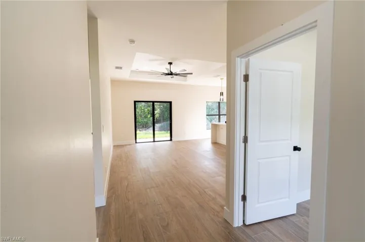 Open concept living area featuring wood-finish flooring, recessed lighting, and a tray ceiling with a contemporary ceiling fan