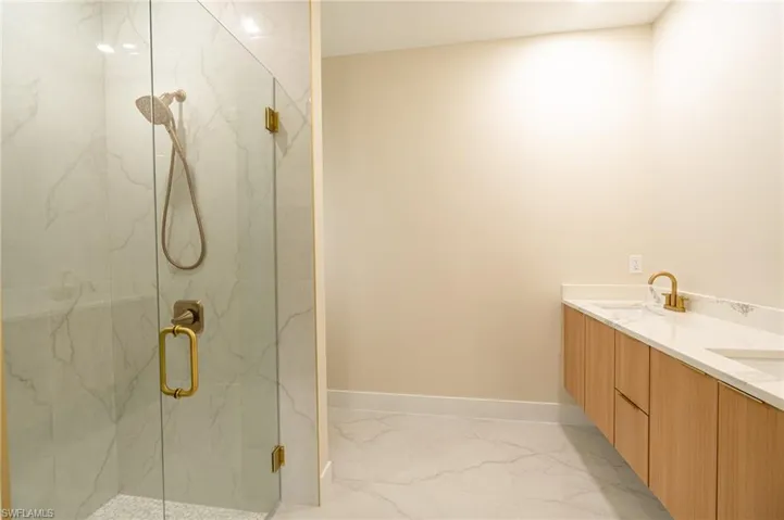 Spacious bathroom featuring a glass-enclosed shower with a handheld showerhead and built-in bench