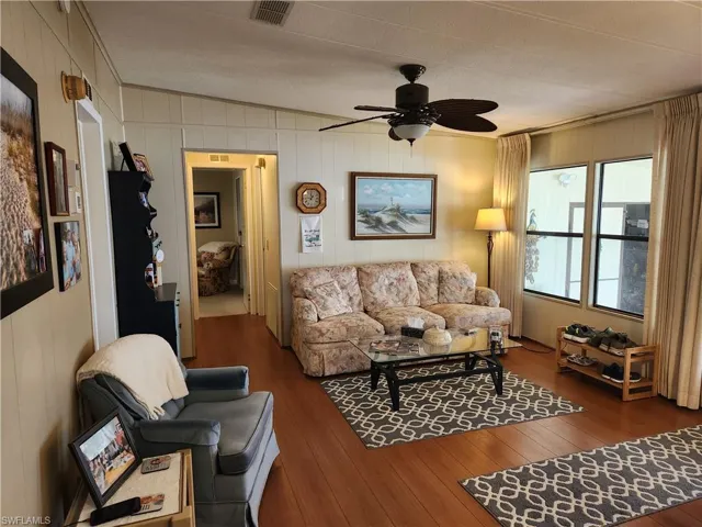 Living room featuring ceiling fan, a textured ceiling, dark hardwood / wood-style floors, and crown molding