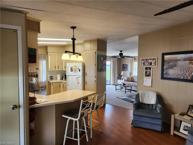 Kitchen with white fridge, a kitchen bar, ceiling fan, pendant lighting, and cream cabinets