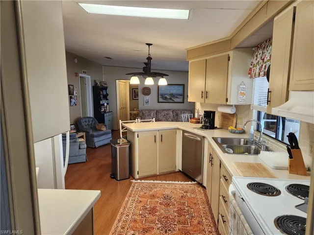 Kitchen with pendant lighting, light hardwood / wood-style floors, sink, cream cabinets, and stainless steel dishwasher