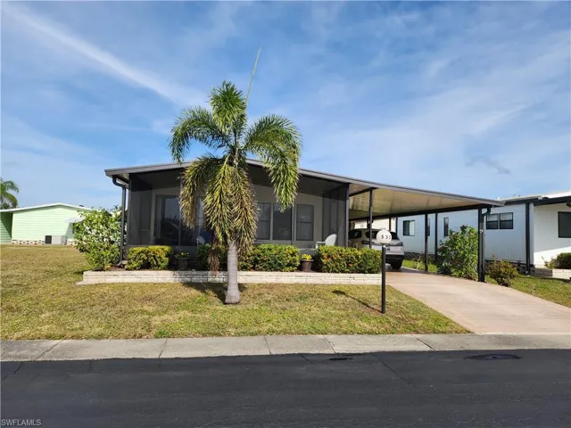 View of front facade featuring a front lawn, a sunroom, and a carport