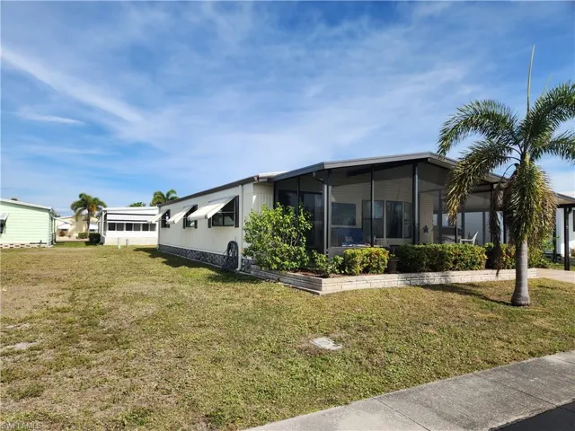 View of front facade with a front yard and a sunroom
