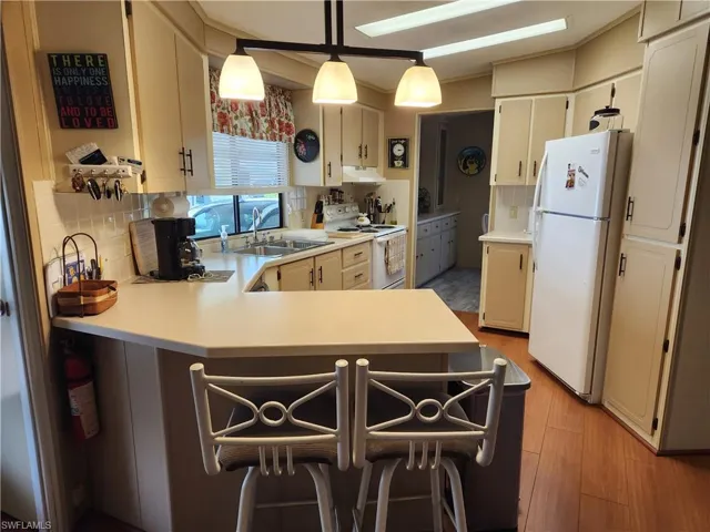 Kitchen featuring sink, white appliances, pendant lighting, and tasteful backsplash