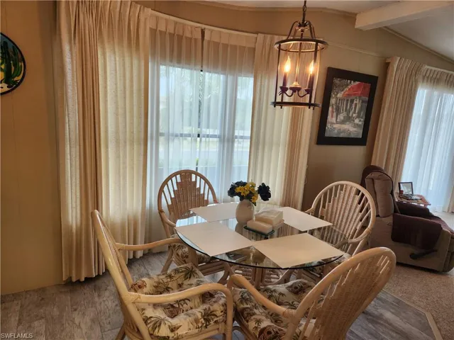Dining room with a chandelier, hardwood / wood-style flooring, and lofted ceiling with beams