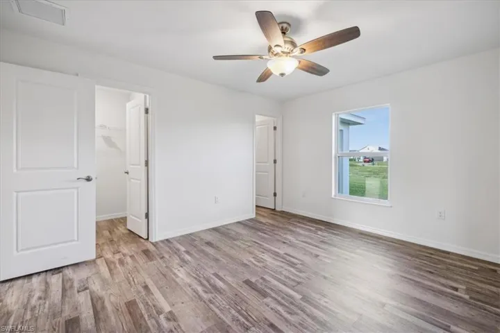 Unfurnished bedroom featuring ceiling fan, a closet, wood-type flooring, and a spacious closet