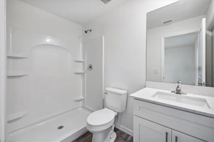 Bathroom with a shower, wood-type flooring, vanity, and toilet