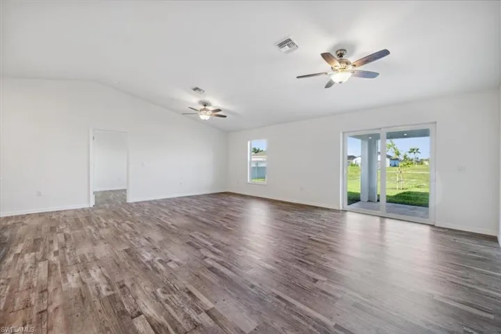 Empty room with lofted ceiling, ceiling fan, and dark hardwood / wood-style flooring